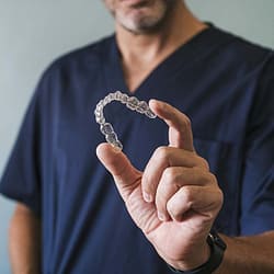 Male orthodontist holding an Invisalign clear aligner