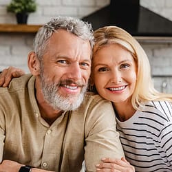 Older couple smiling and sitting close together in a kitchen