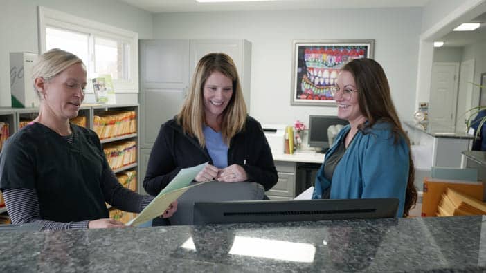 Staff at Bandy Dental looking over paperwork with a patient | Dentist Office in Holly, MI